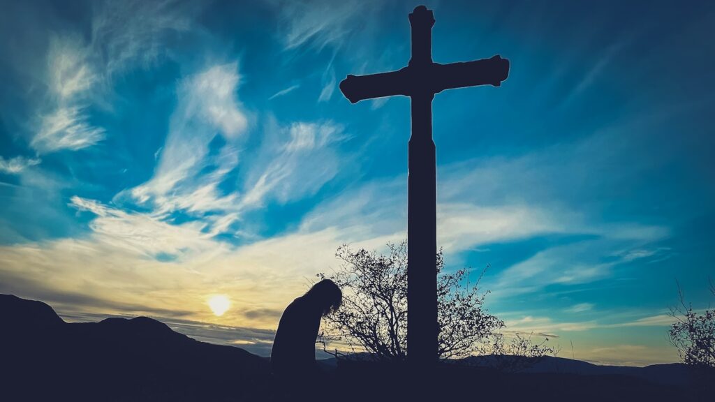 a person kneeling down in front of a cross